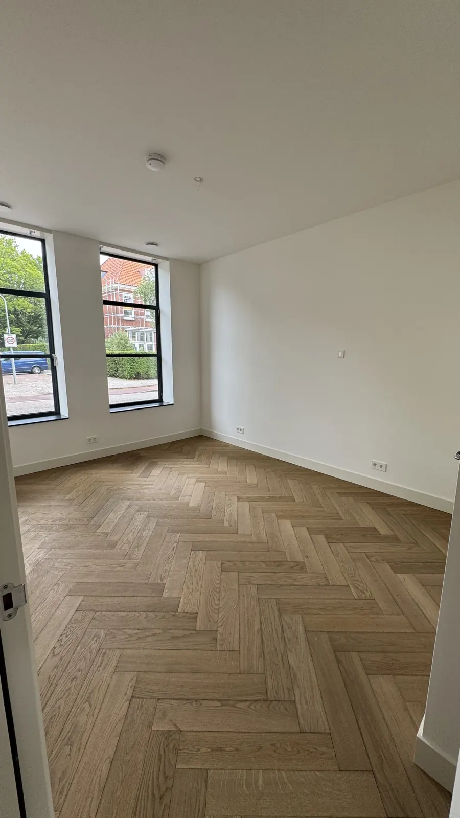 Kamer met strak afgewerkte wanden en stalen ramen, project Haarlem