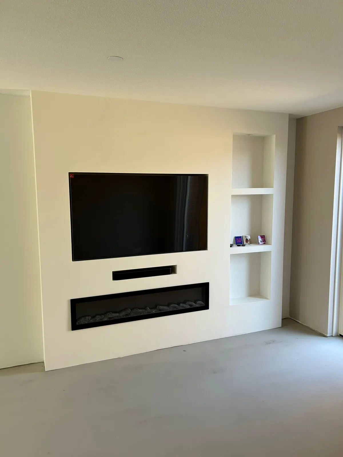 Woonkamer met tv-wand en inbouwhaard na behangen en sauzen, project Zevenhuizen