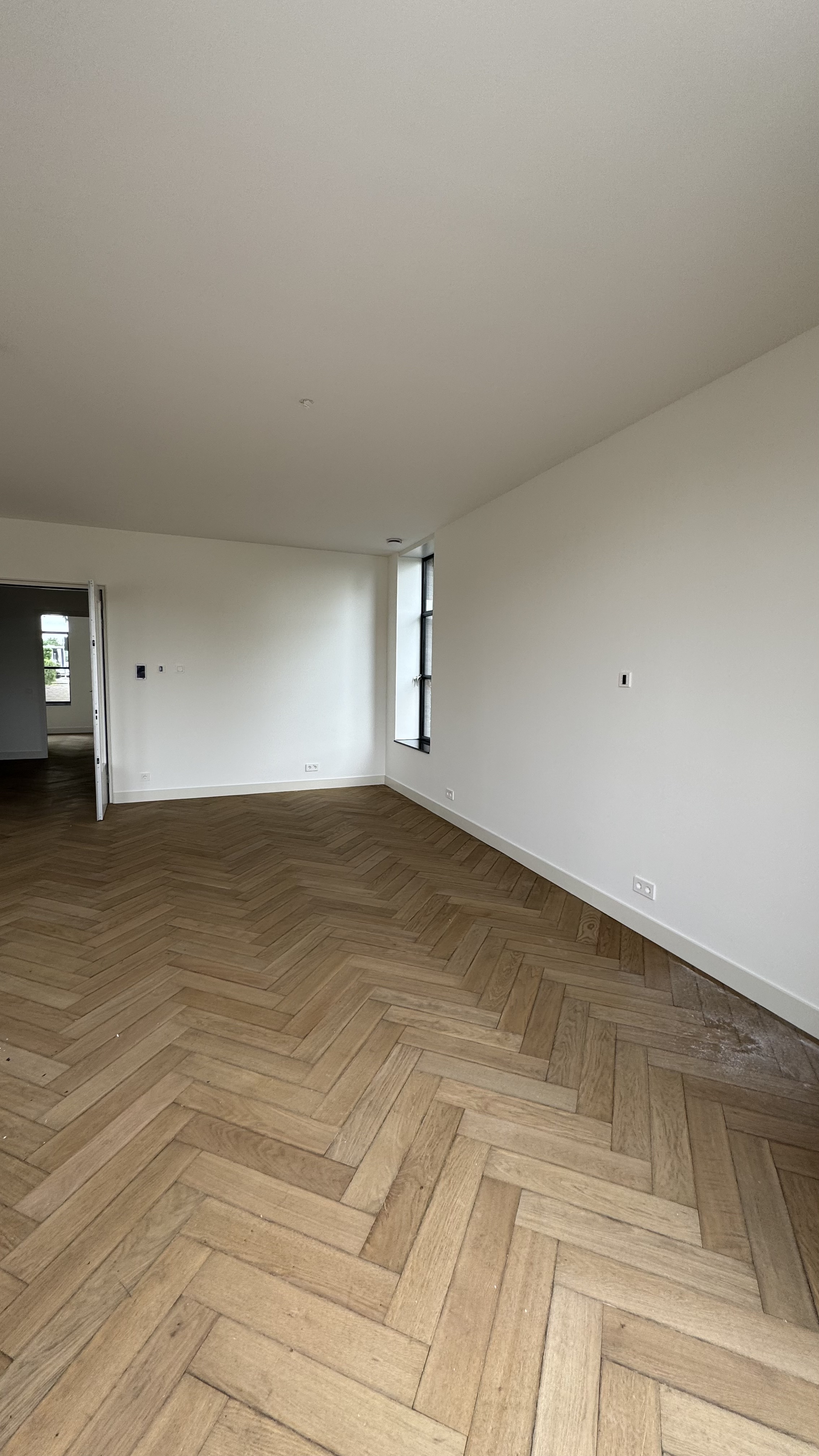 Woonkamer met visgraatvloer en strak wit geschilderde muren renovatie Haarlem