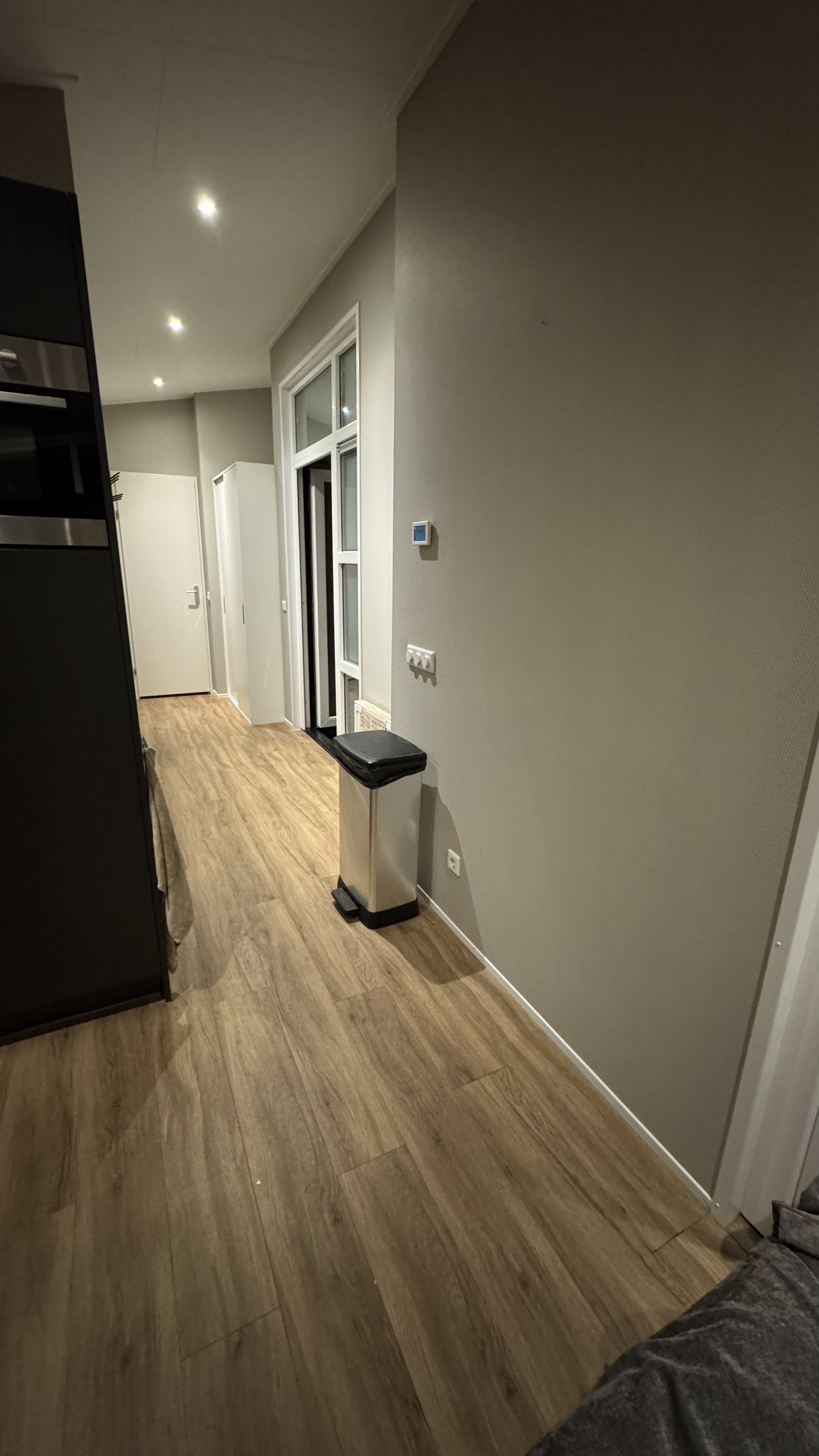 Woonkamer met strak wit geschilderde muren en wandafwerking renovatie Putte Noord-Brabant